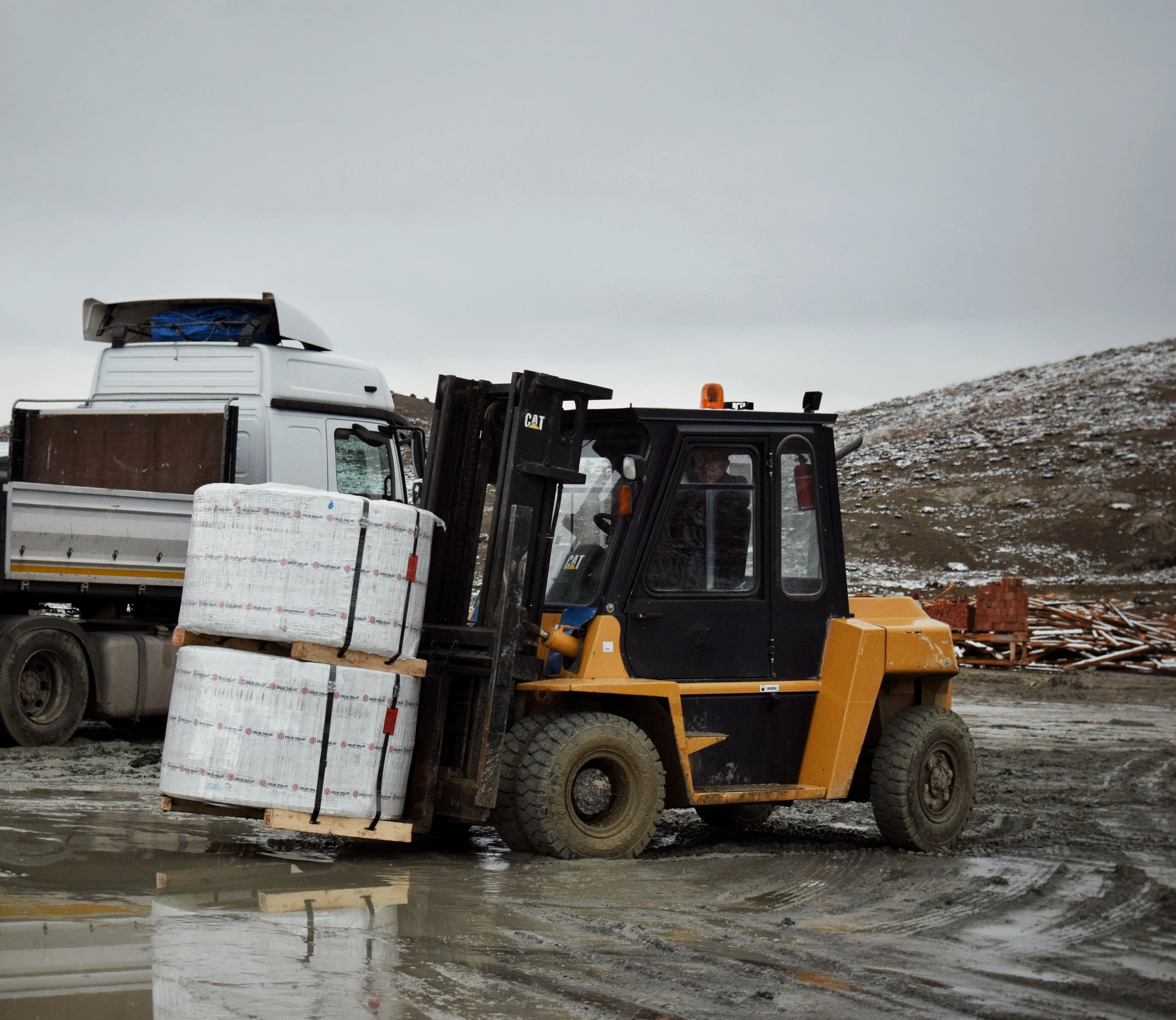 Forklift unloading palletised goods from a delivery truck on site
